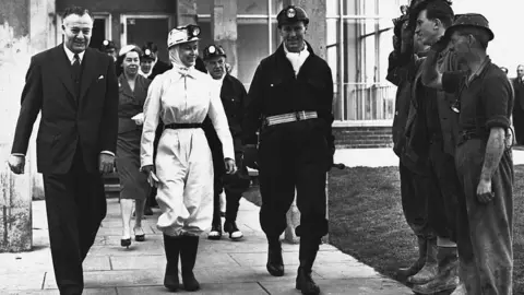 Getty Images The Queen wearing miner's overalls is accompanied by workers before descending the mine at Rothes Colliery in Fife during a visit to the area