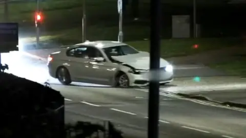 A crumpled car driving into a petrol station