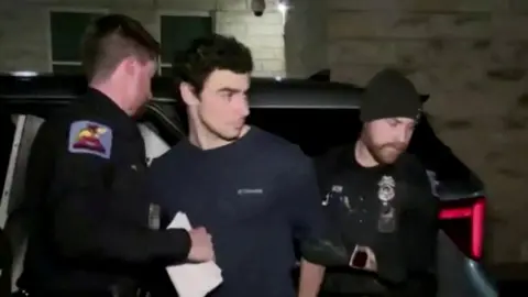 A video grab showing Luigi Mangione arriving for his arraignment at court. He is being escorted by two police officers.