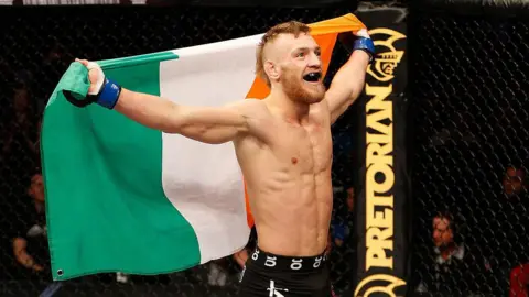 Getty Images Conor McGregor holding the Irish tricolour after winning a fight