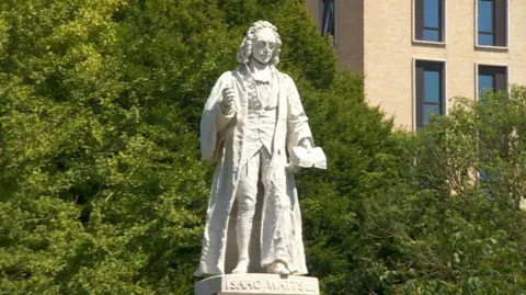 Isaac Watts statue with fixed fingers and in the sunshine in Watts park