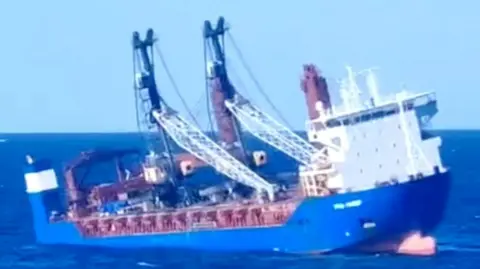 A blue Russian ship lists to starboard in the Mediterranean