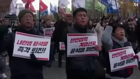 Three protesters holding placards