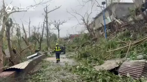 Rescuer amongst debris and fallen trees in the street