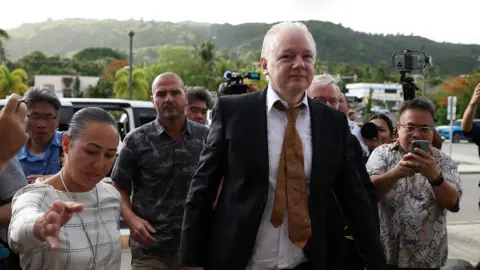 Reuters Julian Assange arrives at court in the Northern Mariana Islands surrounded by people
