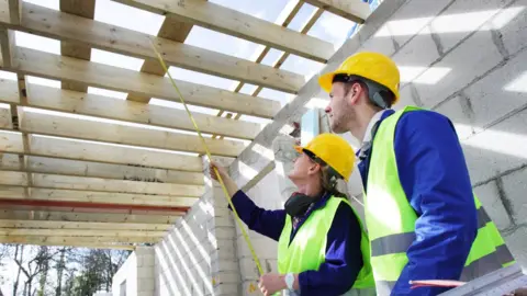 Builders taking measurements in a new house