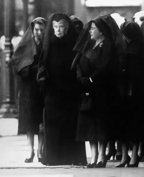 PA Media Queen Mary (centre) watches as the body of her son, George VI, is brought to Westminster Hall, London, for the lying-in-state. By her side, the Queen Mother, right, her eyes closed in grief. Queen Elizabeth II, veiled, stands behind her grandmother.