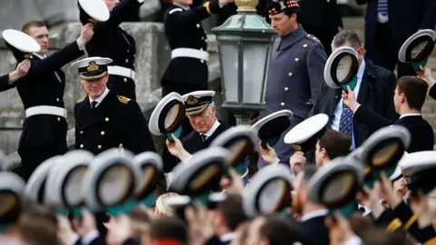 PA Media Britannia Royal Naval College officers raising their hats to the Prince of Wales.