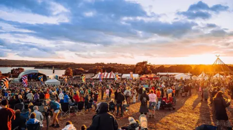 Ania Shrimpton/PR  A crowd of people at a festival at sunset 