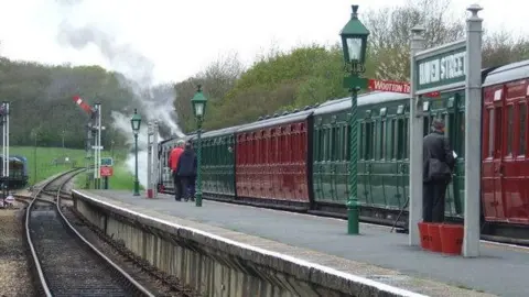 Malc McDonald A steam train at Havenstreet station with alternate carriages painted red and green.