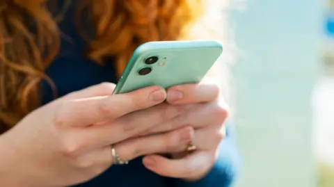 Woman holding turquoise iPhone in both hands with finger touching the screen