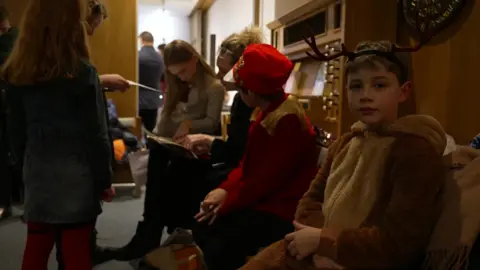 child smiles at camera at christmas school concert