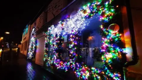 BBC Weather Watchers/Smiley Sue Christmas lights attached to the outside of a shop