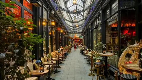 BBC Weather Watchers/Nadezna The interior of a shopping mall with Christmas decorations each side