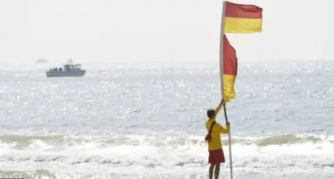 PA Media A lifeguard erecting a patrol flag at the seashore