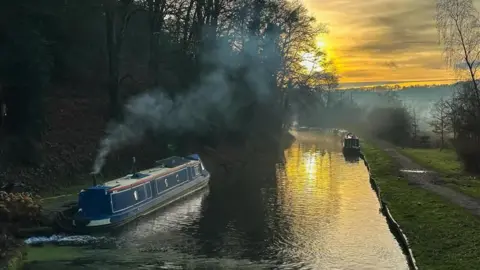 BBC Weather Watchers/sabphotos69 A river with a houseboat on and the sun setting