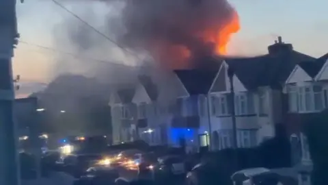 Flames and smoke from the roof of a home