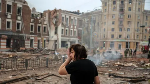 A woman wipes her eye in front of debris in Kharkiv, eastern Ukraine, in October