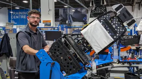 Eoin Murray, operations manager at Thompson Aero Seating, stands next to a jig holding a partly assembled airline seat