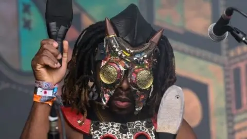 A member of the Democratic Republic of Congo band Fulu Miziki adjusts his mask