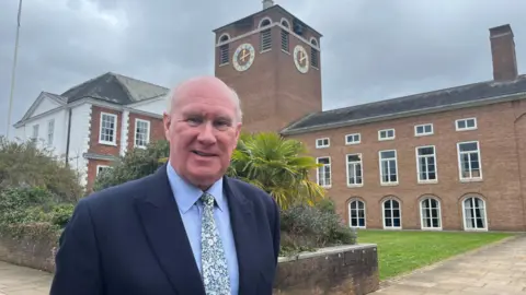 James McInnes, leader of Devon County Council, wearing a patterned tie, blue shirt and blue blazer