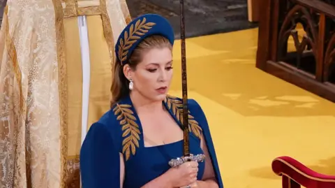 Penny Mordaunt holding a sword at the coronation of King Charles III
