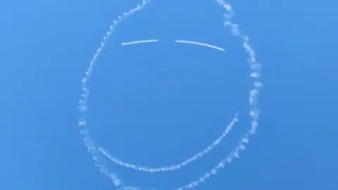 Smiley face drawn in sky by plane vapour trail.