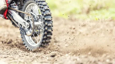 A motocross bike rolls stones and mud at the start of the race - stock photo