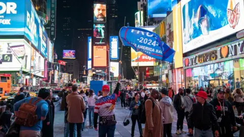 Getty Images A pro-Trump supporter holds a banner in Times Square on election day, 5 November in New York City. 