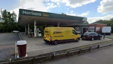 Street view of Morrisons Daily in Totnes with a yellow van and black car at the filling station