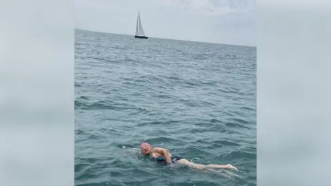 Aspire woman swimming in sea with boat in background