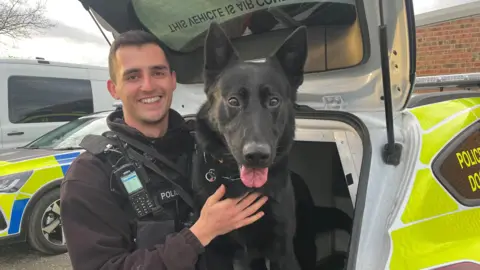 Corinne Wheatley A police dog handler with his dog