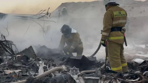 Ministry of Emergencies for the Republic of Kazakhstan Firefighters examining and looking through debris from a plane crash