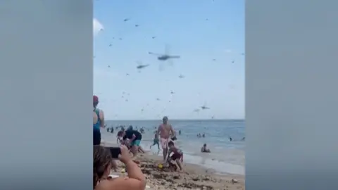 Dragonflies are seen storming a beach in Rhode Island. Beachgoers are seen taking videos.