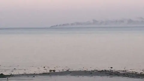 Smoke on the horizon from an out-of-view vessel, seen from the County Down coast