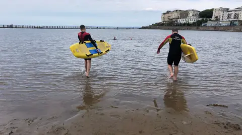 RNLI Two RNLI lifeguards with surfboards in the water 