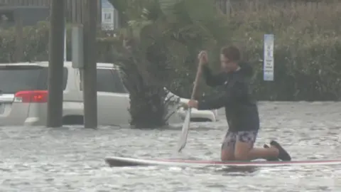 Boy is paddling on a surfboard.