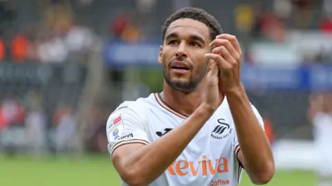 Swansea City defender Ben Cabango applauds