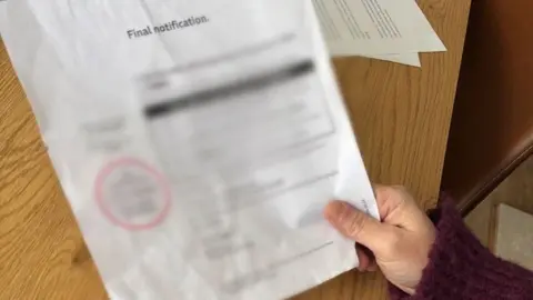 A hand holding a letter with blurred out writing. it says final notification at the top of the letter