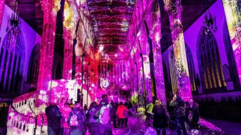 Last year's light show at Hull Minster, with purple and pink colours projected onto the walls of the building, while crowds of people stare at them