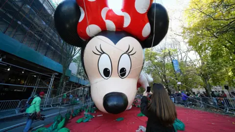 A woman is taking a picture of a balloon.