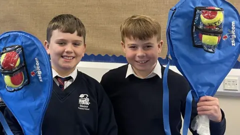 Manor Primary School Two schoolboys smiling with their tennis tackets.