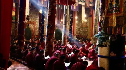 Tsering Woeser A photo showing seated red-robed monks praying inside the Wontoe Monastery in Dege county. 