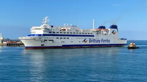 A big white ferry with Brittany Ferries logo on the side, in the ocean.