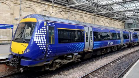 blue and yellow scotrail train at empty station platform