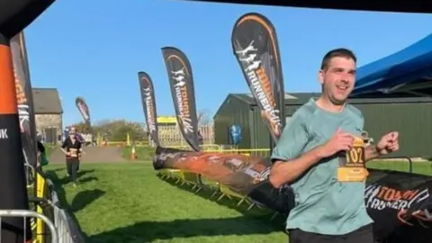  Kieron Brosnan Picture shows Kieron crossing the finishing line of a 'tough runner' event 