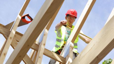 Builder working on roof of house (stock photo)