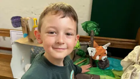 Shaun Whitmore/BBC Elliott standing near his model of a red panda