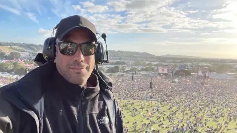 Man taking a selfie in a crane above the Pyramid Stage at Glastonbury Festival