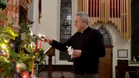 Rev Matt Woodcock, vicar at St Stephen's Church in York, lights a candle from one to another inside a church.